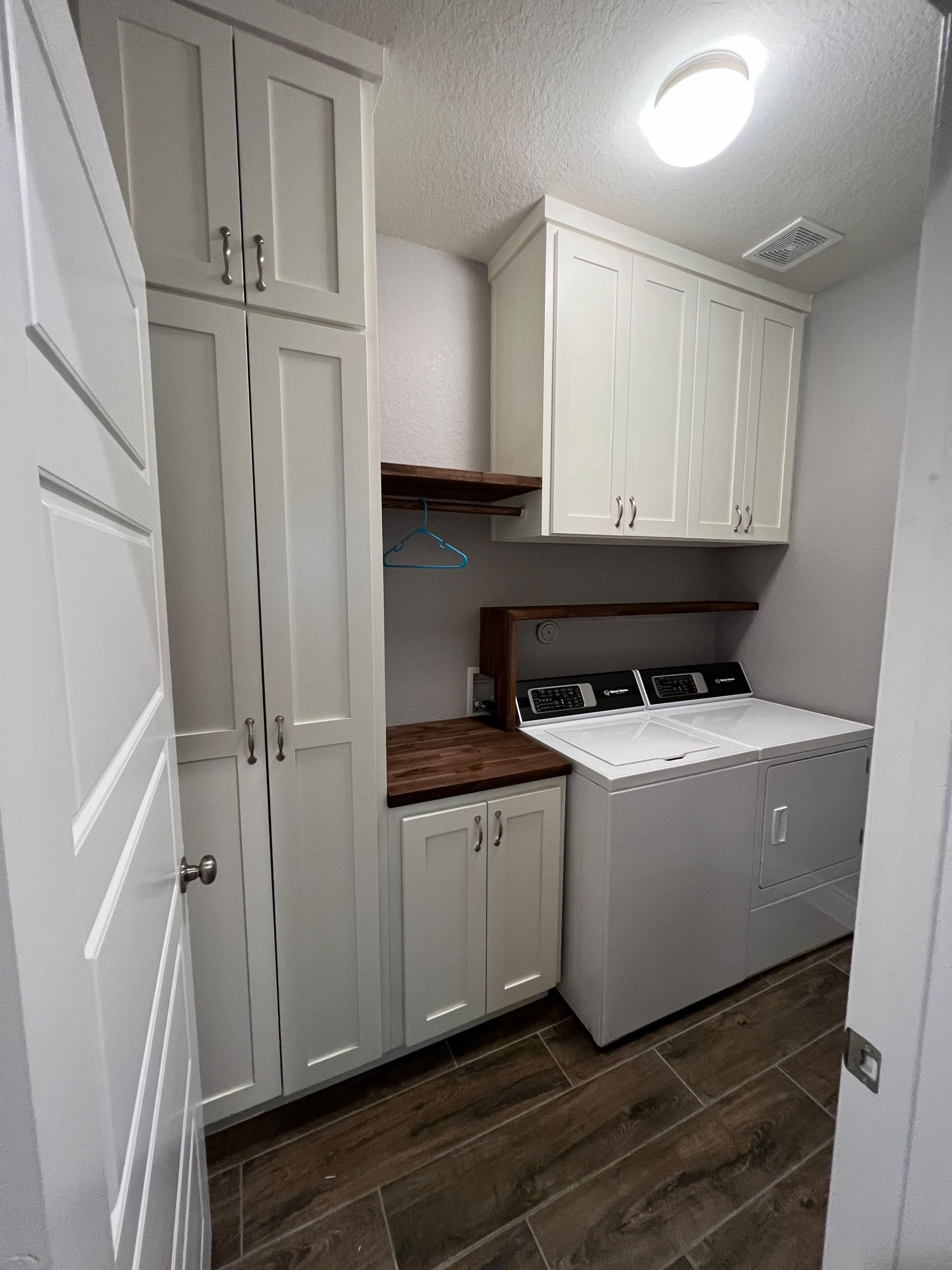 Laundry room with white cabinets, washer/dryer, and a dark wood countertop.