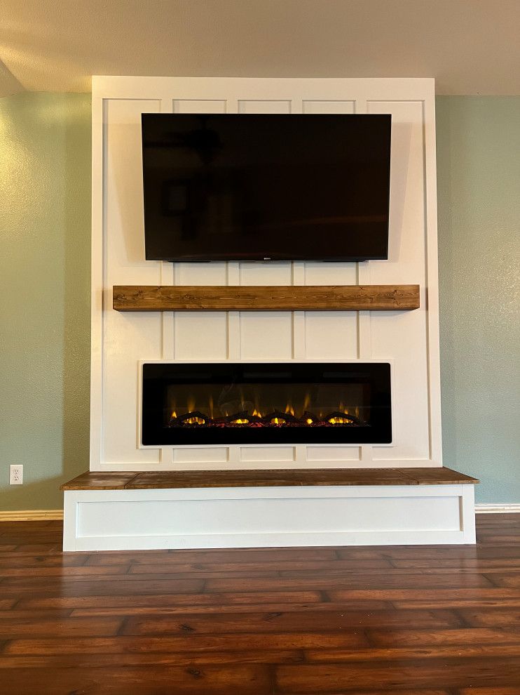 A modern fireplace with a mounted TV, dark wood mantel and base, and a white paneled wall.