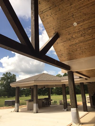 Outdoor patio with dark wooden beams, gazebo, and blue sky.