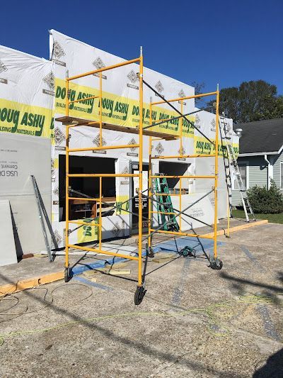 Yellow scaffolding in front of a building under construction. Blue sky, cement ground.