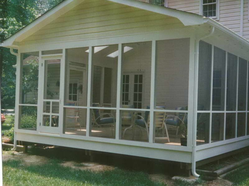 Screened porch addition to a house. White trim, green lawn, and clear sky visible.