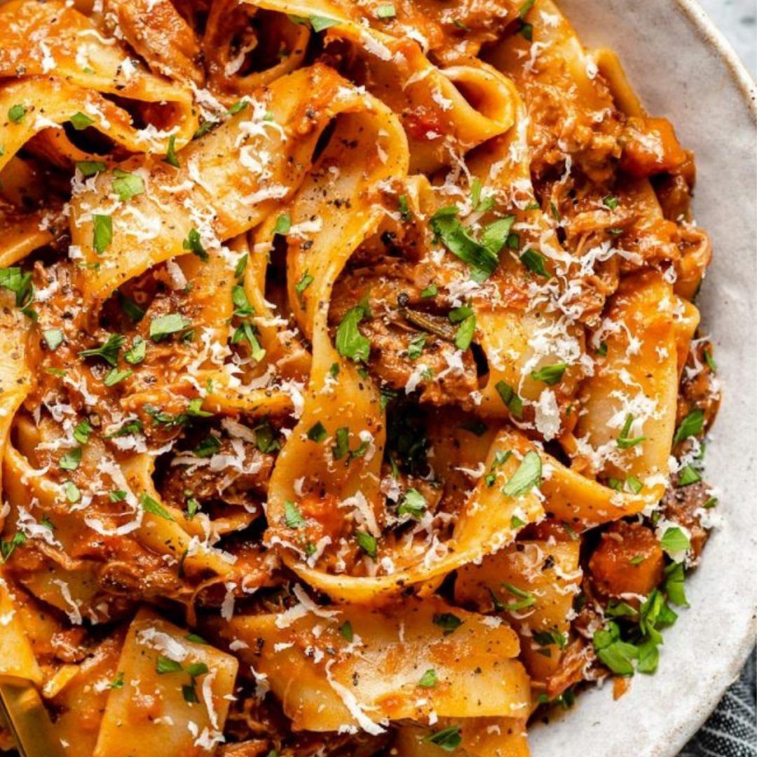 a close up of a bowl of pasta with meat sauce and cheese .