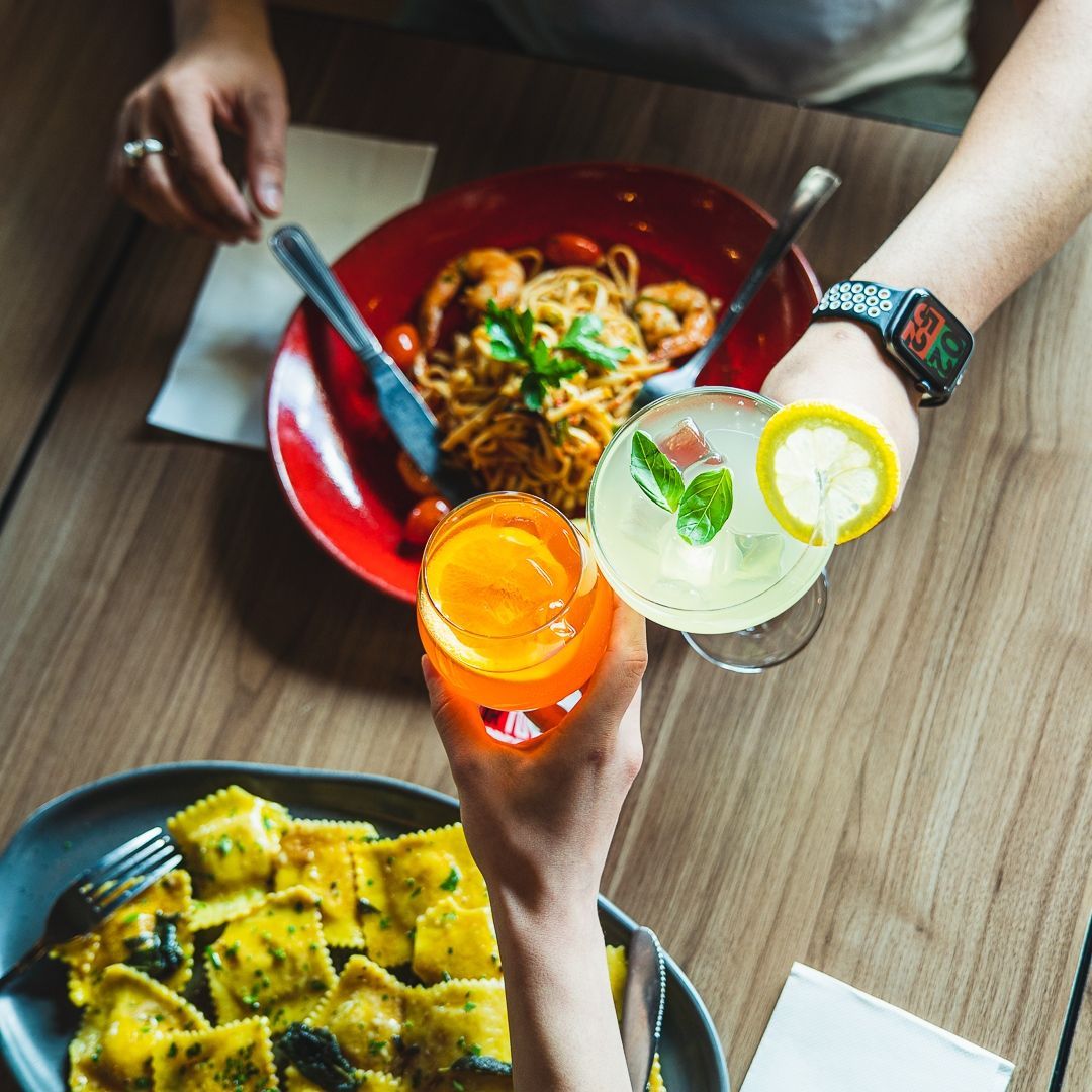 Italian man wearing an apple watch toasts with two drinks and a plate of food