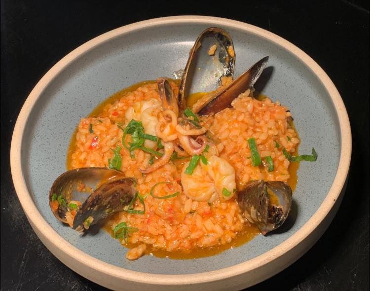 a blue bowl filled with rice and seafood on a table