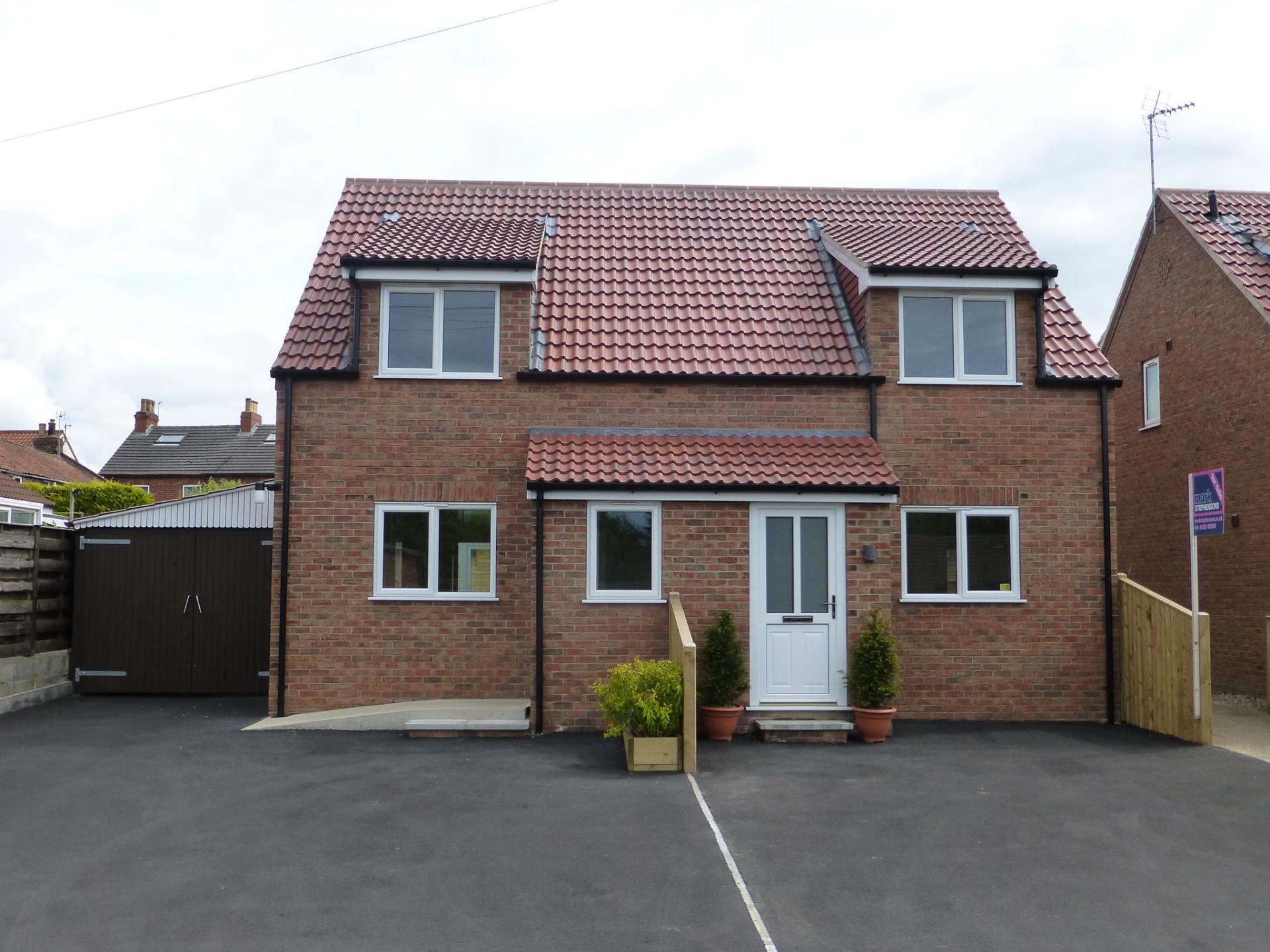 A brick house with a red tiled roof and white windows