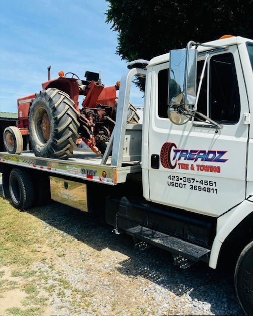 A tow truck with a tractor on the back of it