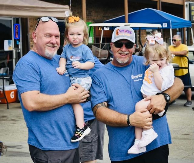 Two men are holding two little girls in their arms.