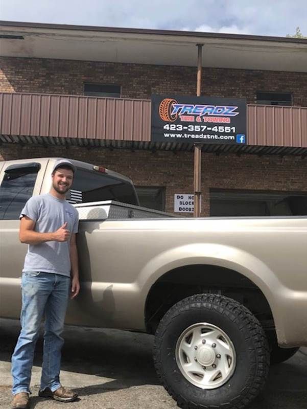 A man is standing next to a truck in front of a building.