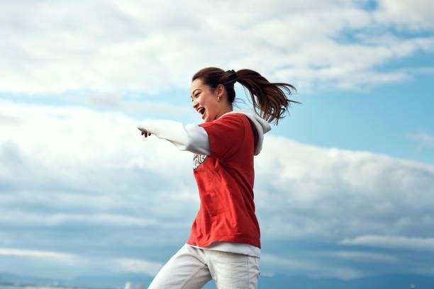 A woman in a red shirt and white pants is jumping in the air.