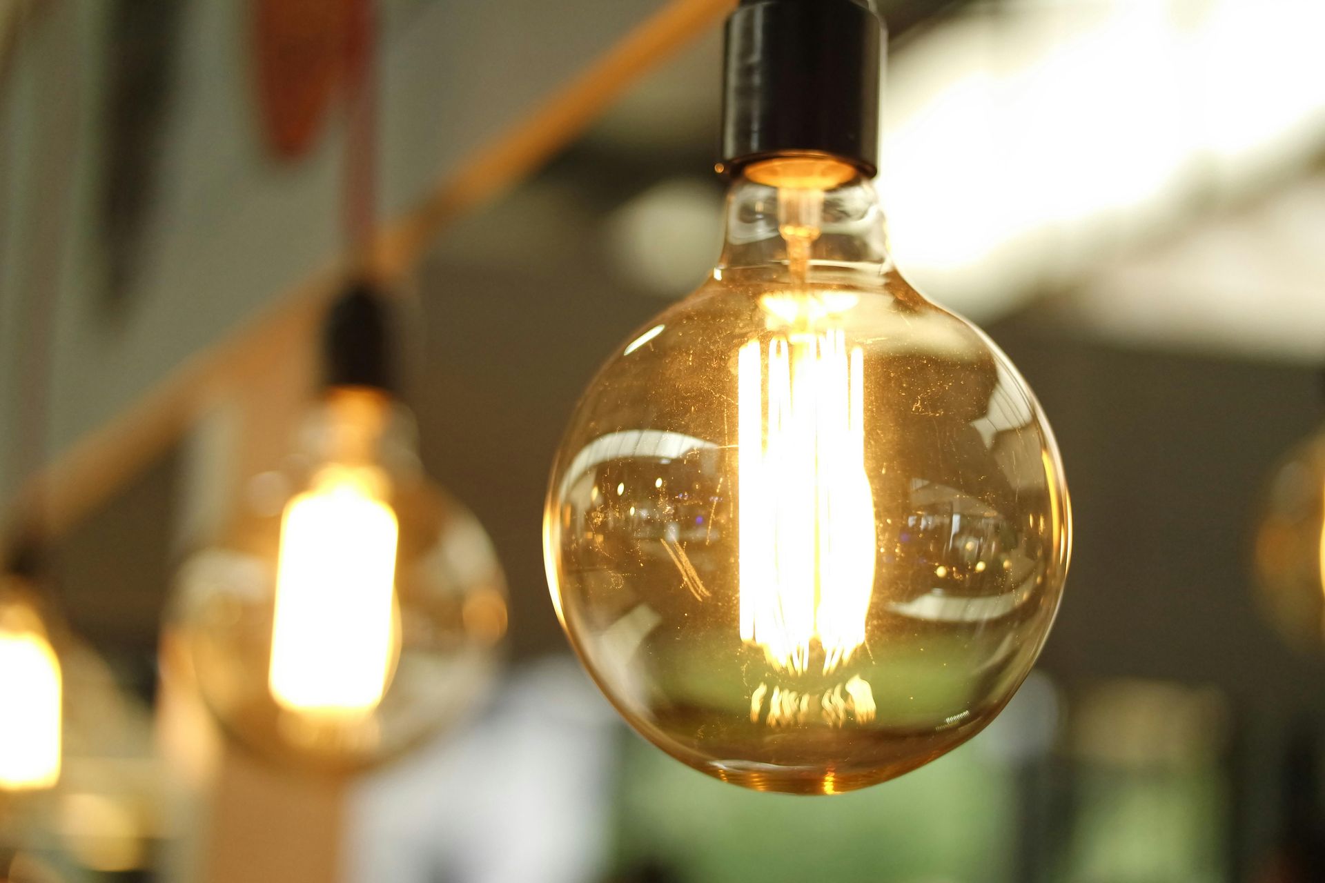 Warm, glowing Edison-style light bulbs hang in a row against a soft-focus background.