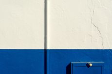 Blue mailbox on blue and white painted wall.
