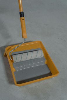 Yellow paint roller and tray with grey paint, handle extended.