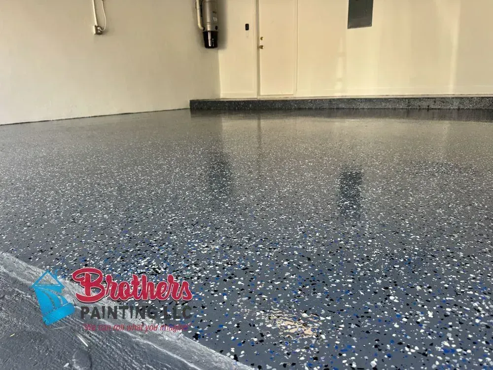 Blue-speckled epoxy garage floor with a glossy finish and a wall base trim.