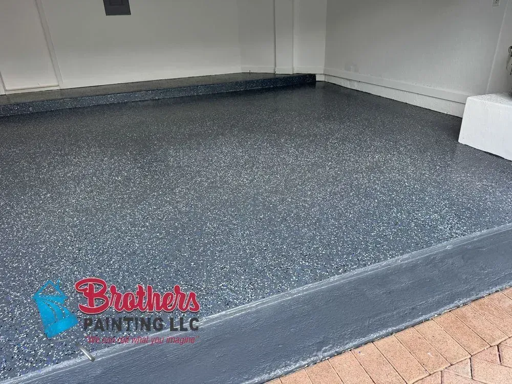 Garage with gray speckled epoxy floor and red-brick driveway at the entrance
