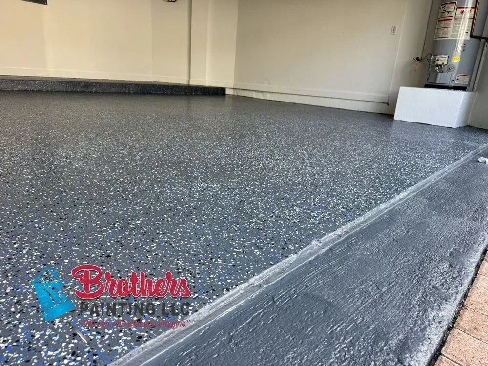 Speckled epoxy garage floor with a sloped ramp edge and a red Bruntco logo watermark