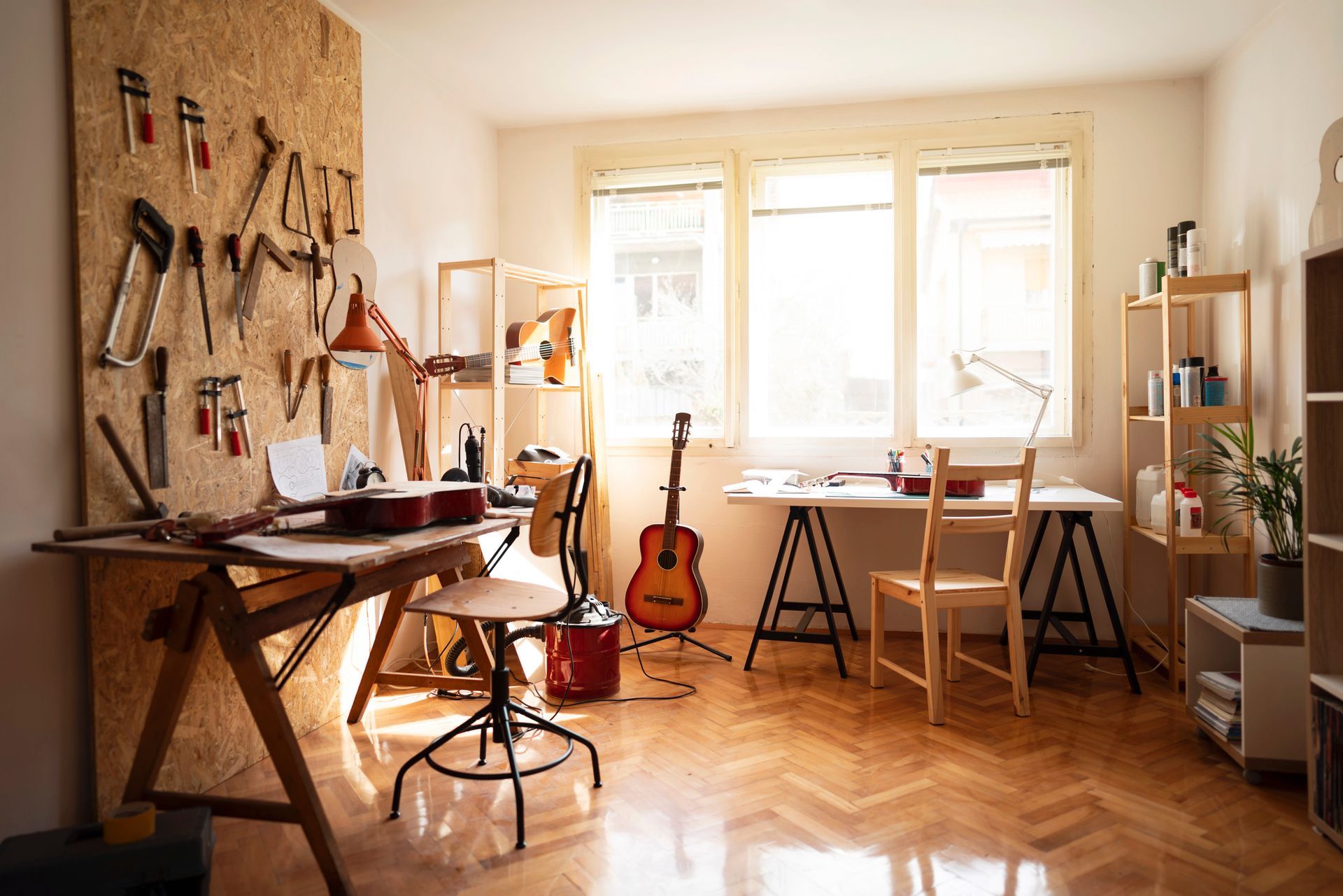 A room with a guitar on a stand and a guitar on a table.