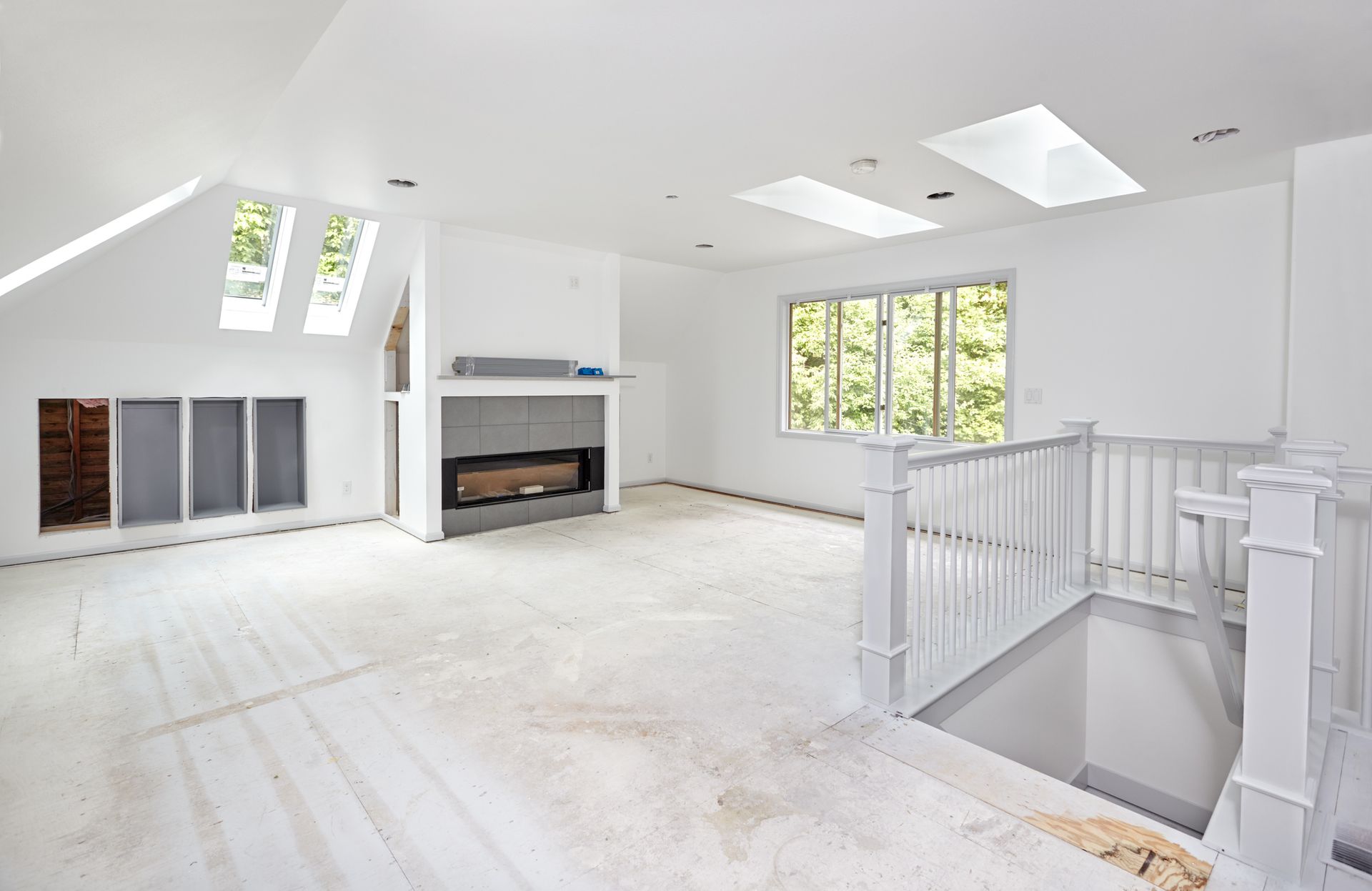 An empty living room with a fireplace and stairs.