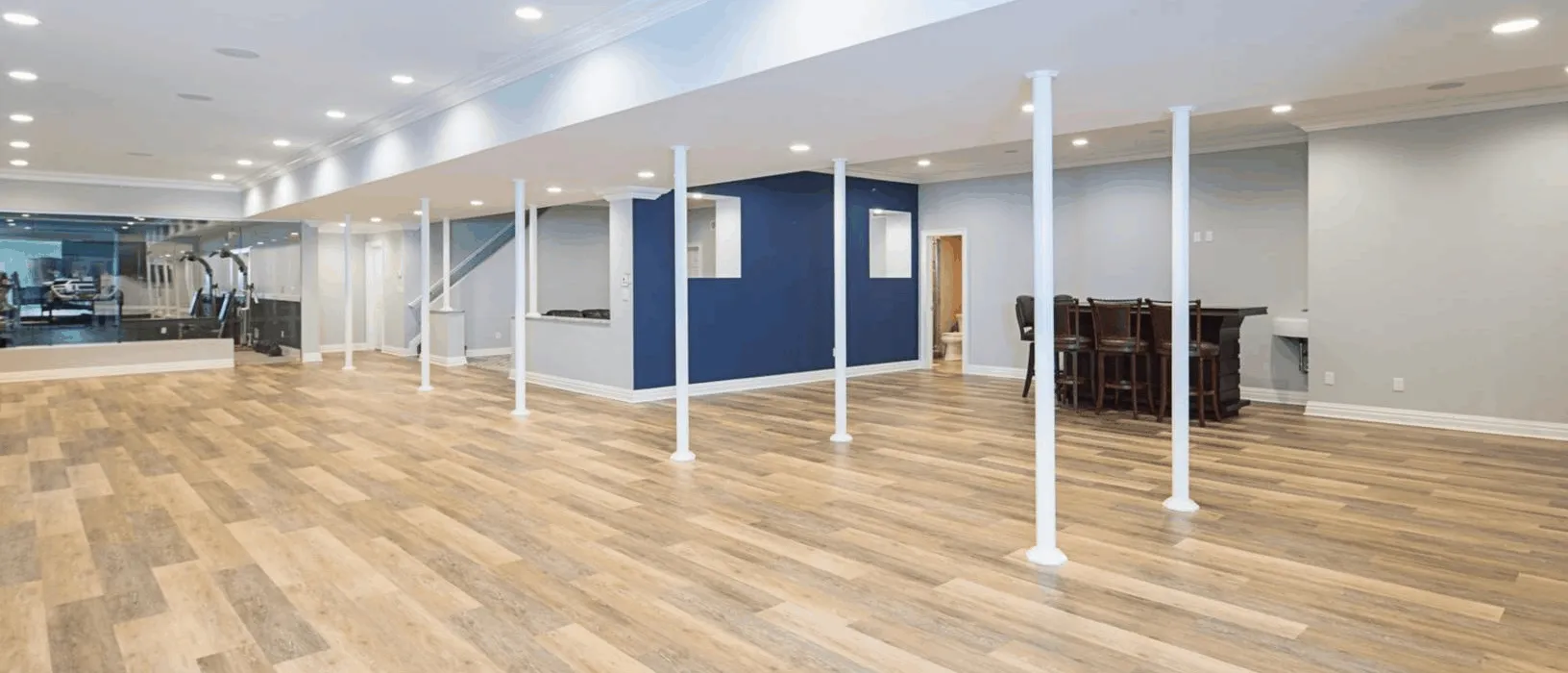 A large empty basement with hardwood floors and blue walls.