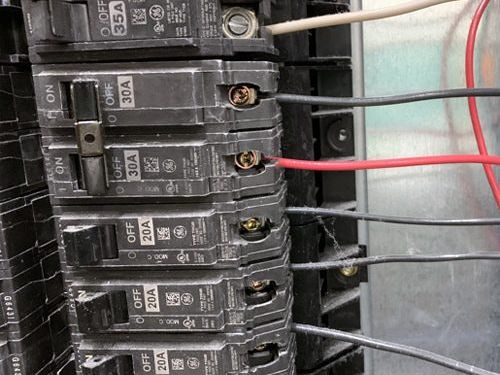 A row of electrical breakers with wires connected to them.