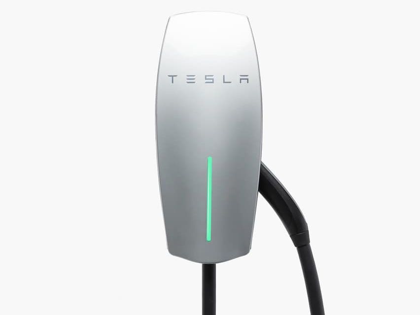 A tesla charging station with a green light on it