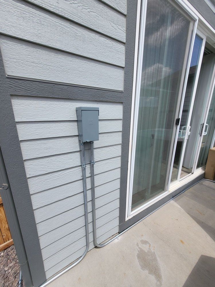 There is a box on the side of a house next to a sliding glass door.