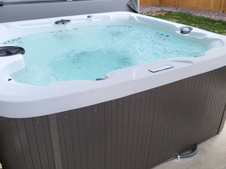 A white and brown hot tub is filled with blue water.