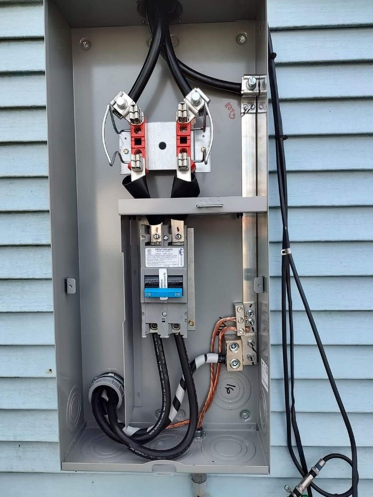 A electrical box on the side of a house with wires coming out of it