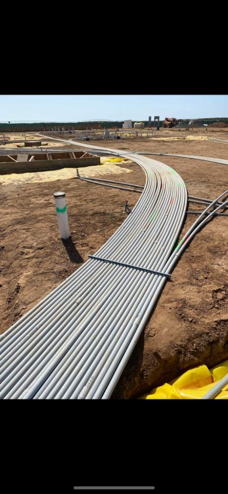 A bunch of pipes are laying in the dirt on a construction site.