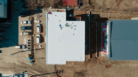 An aerial view of a building under construction with a white roof.