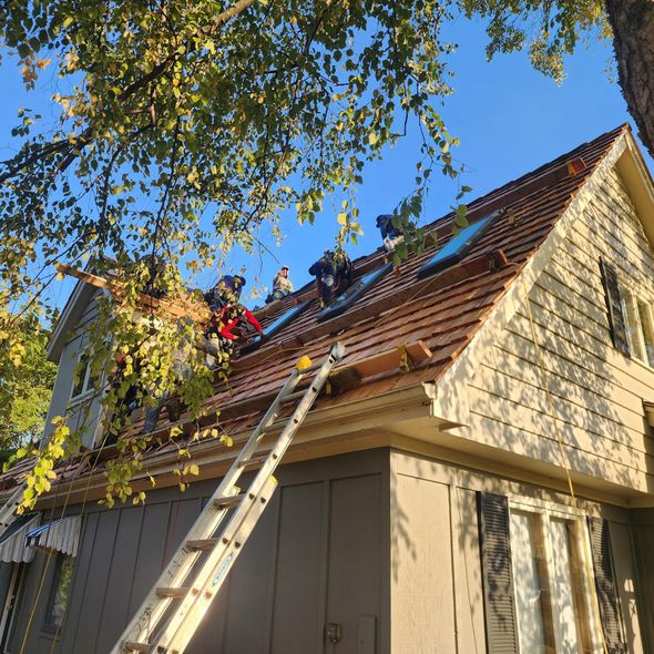 A group of people are working on the roof of a house.