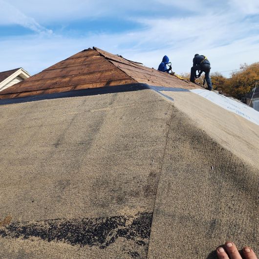 Two men are working on the roof of a house.