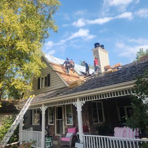 A group of people are working on the roof of a house.