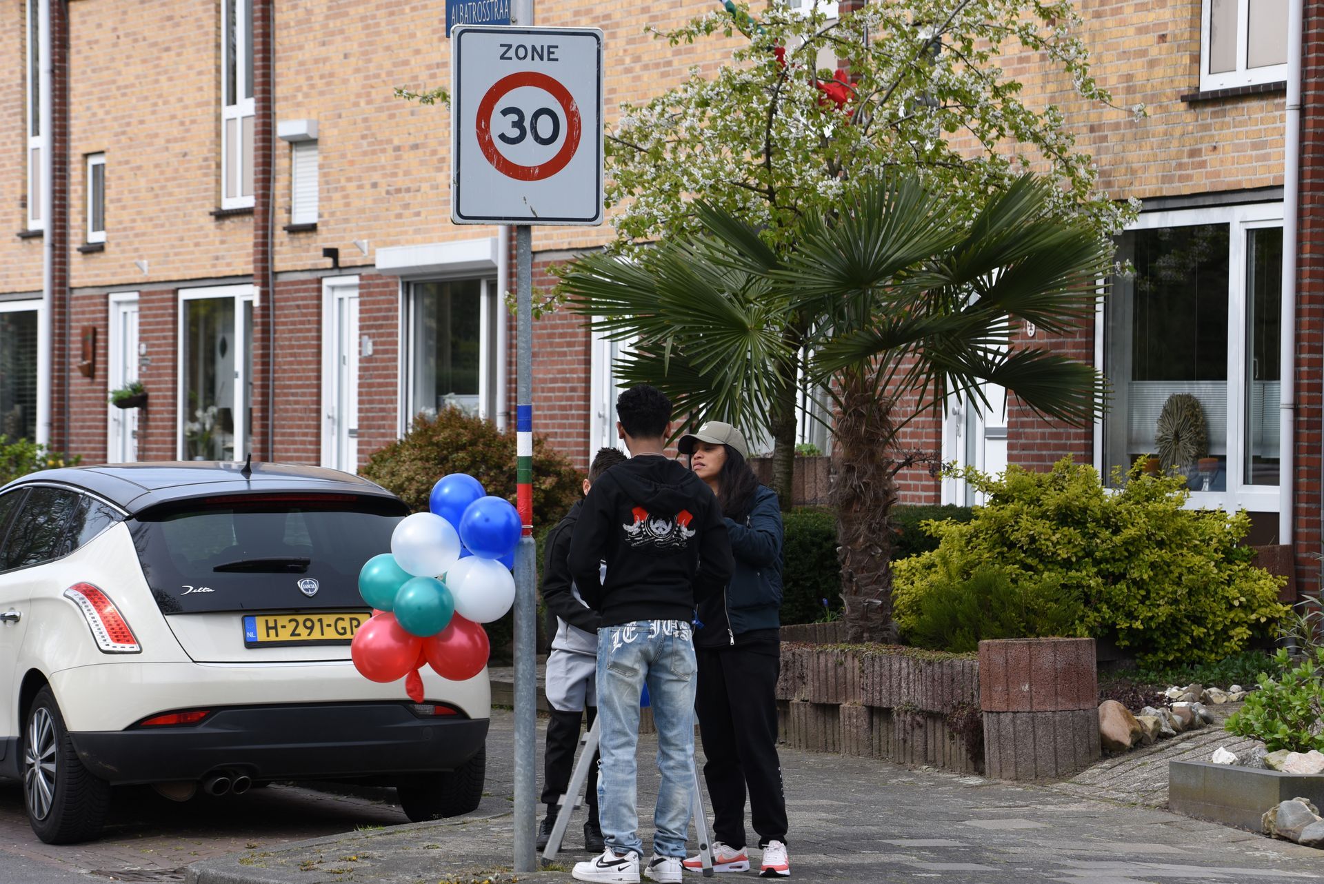 Een groep mensen staat voor een met ballonnen versierde auto.