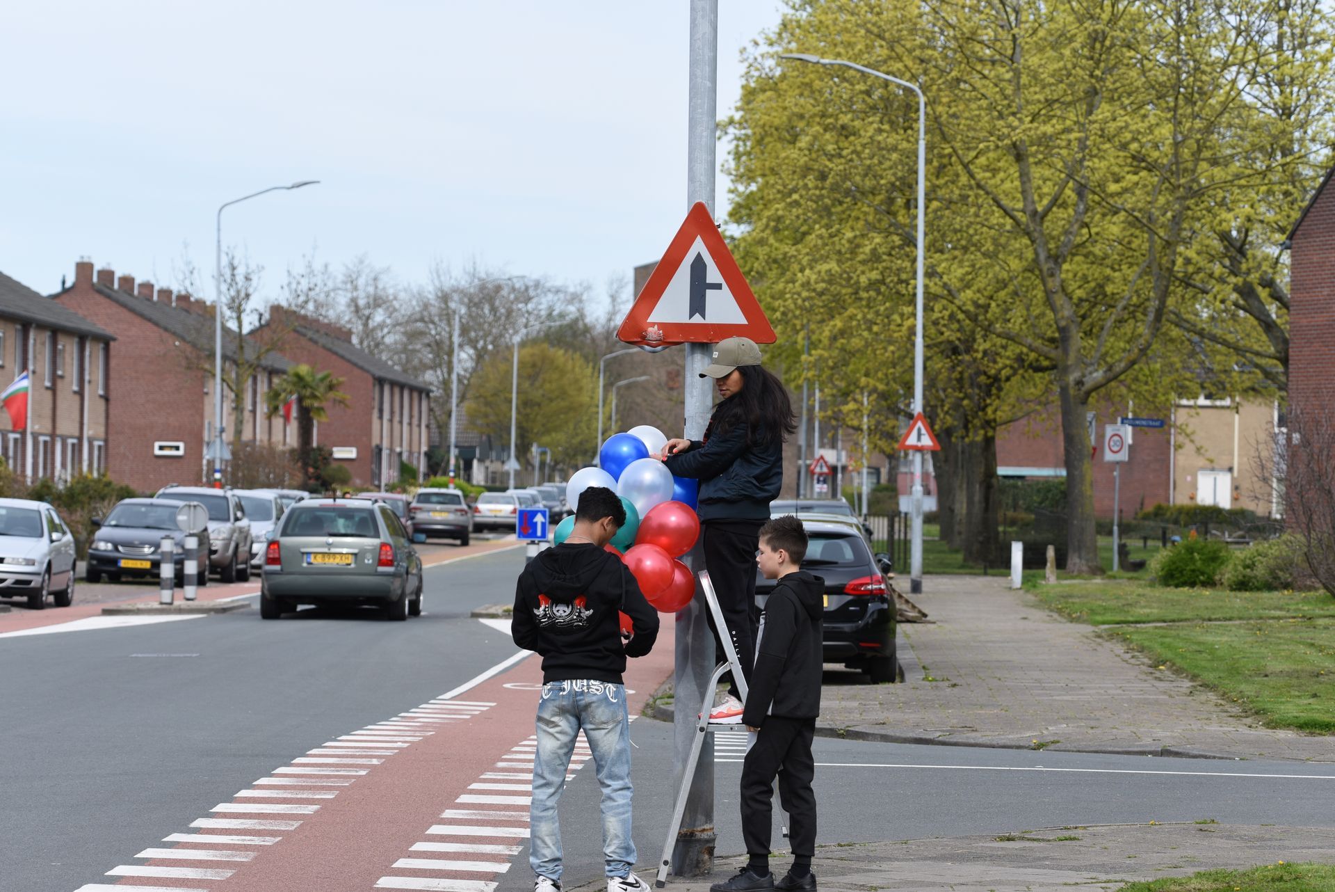 Midden op straat hangt een man ballonnen aan een paal.