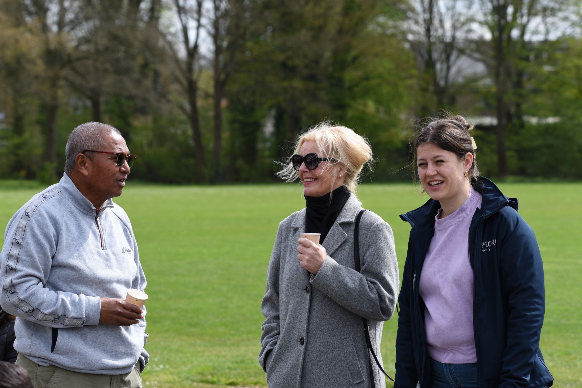 Een groep mensen staat in een veld met elkaar te praten.