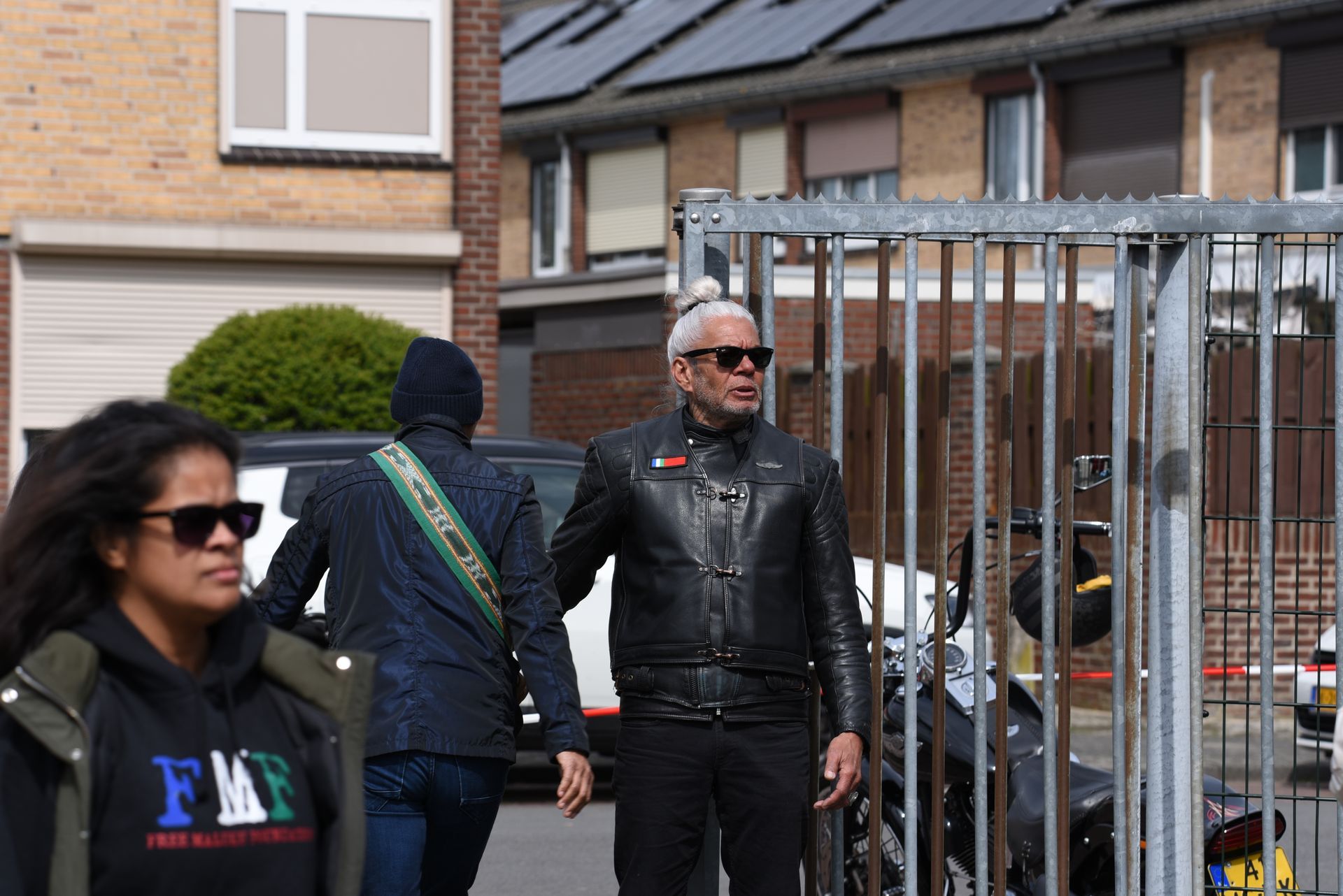 Een groep mensen loopt door een straat voor een hek.