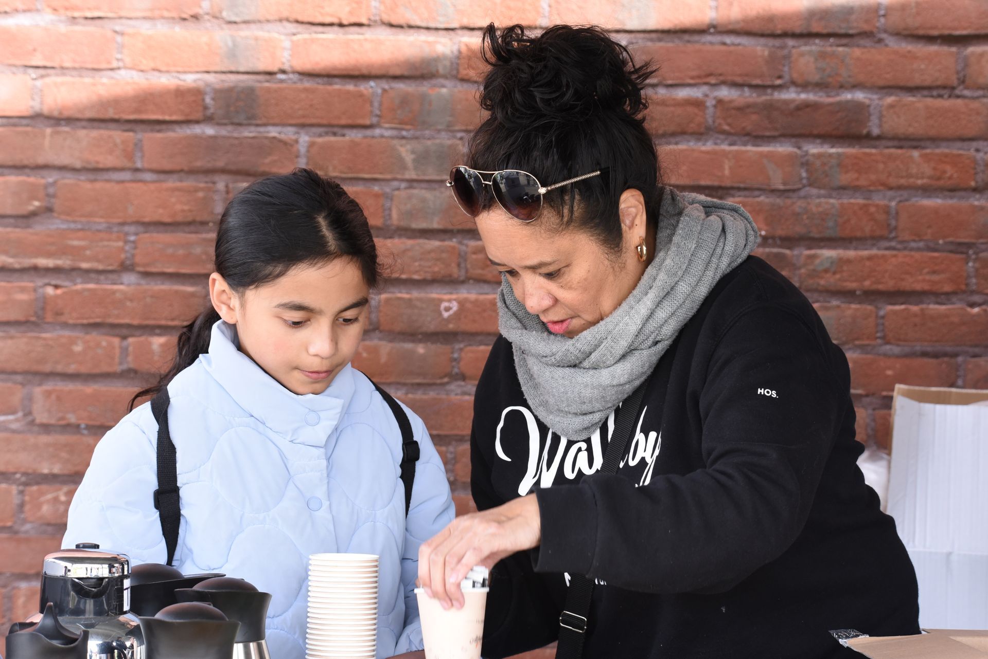 Een vrouw en een meisje zitten aan een tafel met kopjes koffie.
