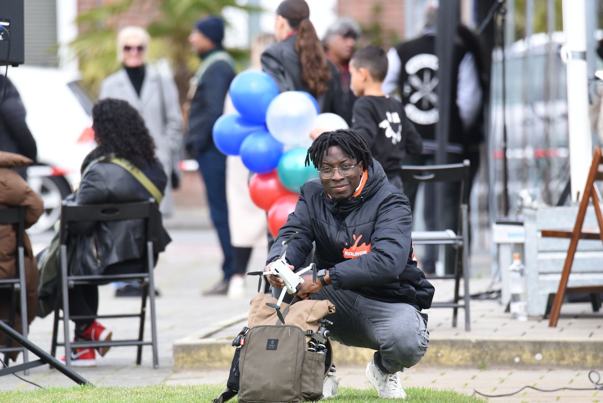 Een man knielt neer en houdt een afstandsbediening vast voor een menigte mensen.