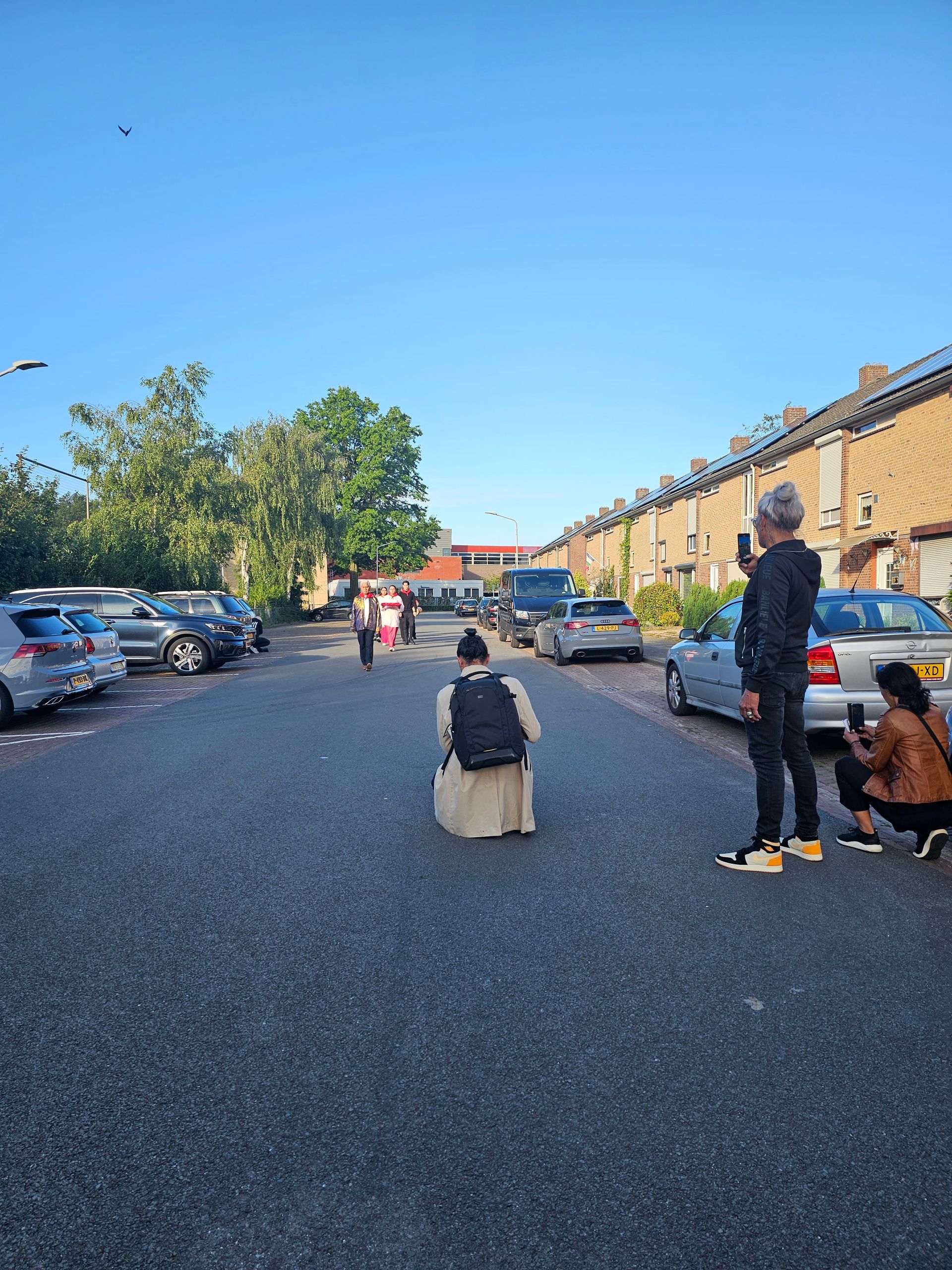 Een groep mensen staat aan de zijkant van een parkeerplaats.