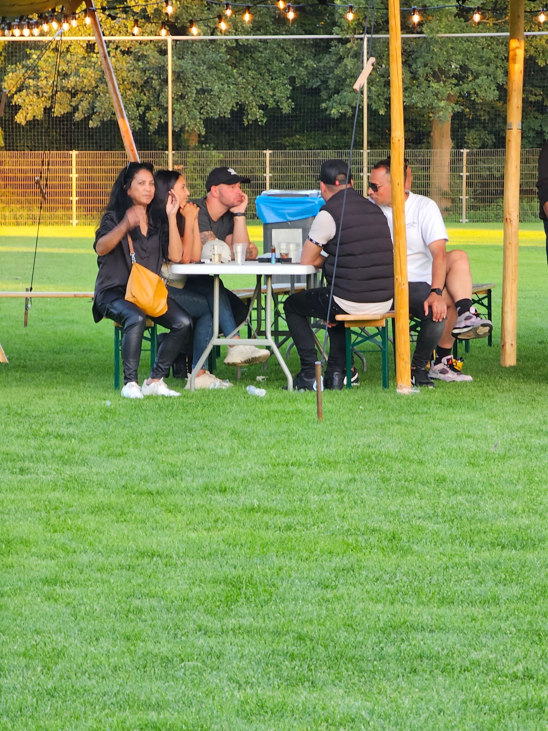 Een groep mensen zit aan een tafel in een park.