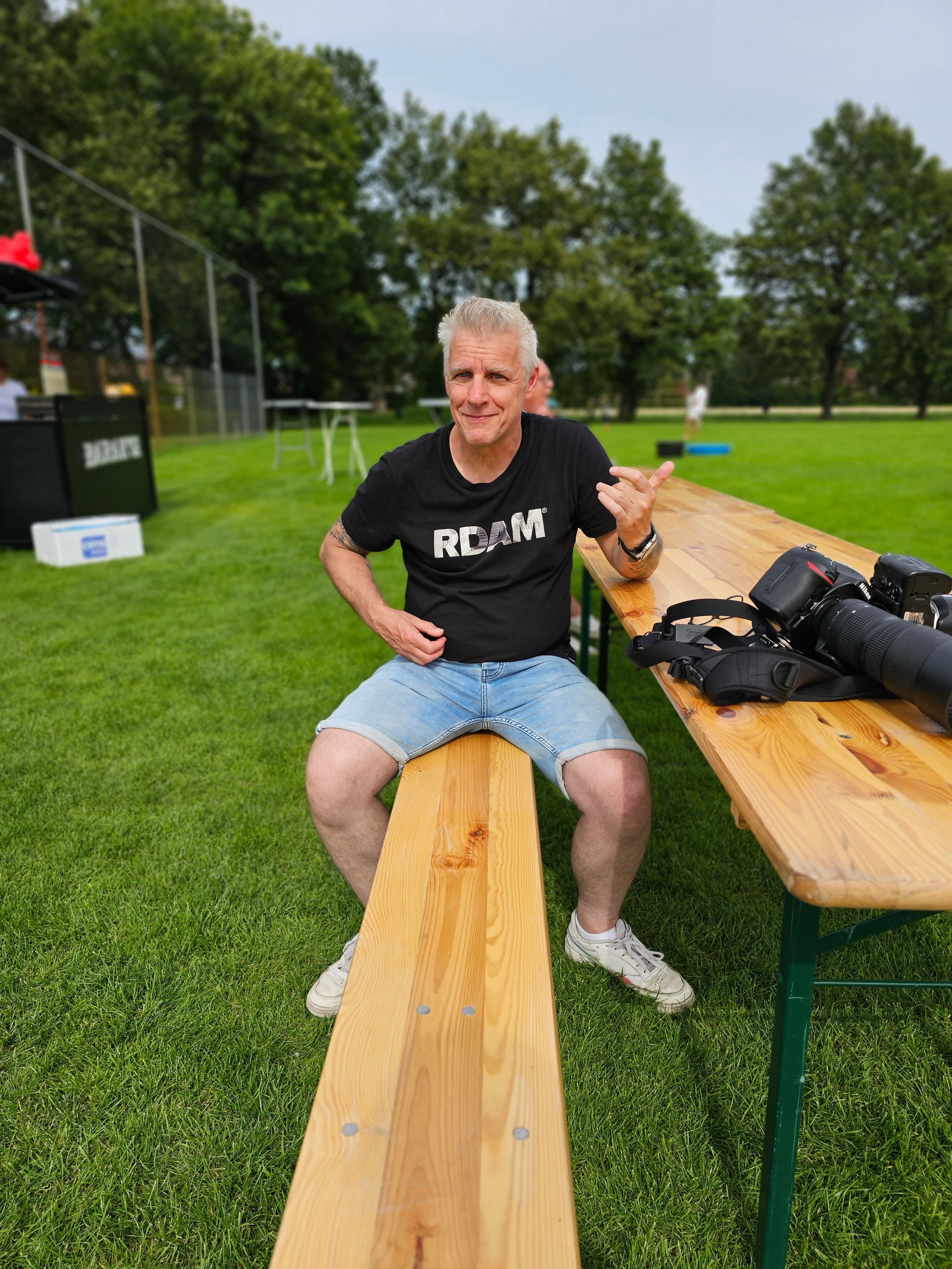 Een man in een zwart shirt zit op een houten bankje