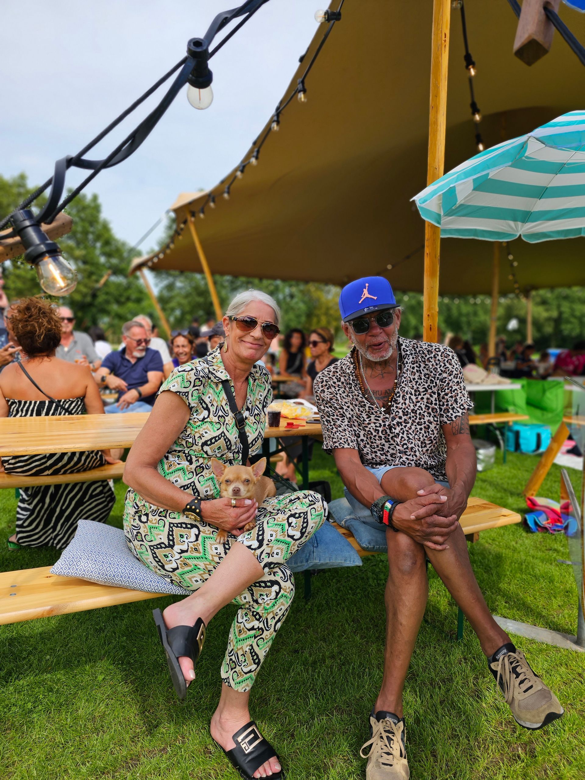 Een man en een vrouw zitten op een bankje onder een tent.