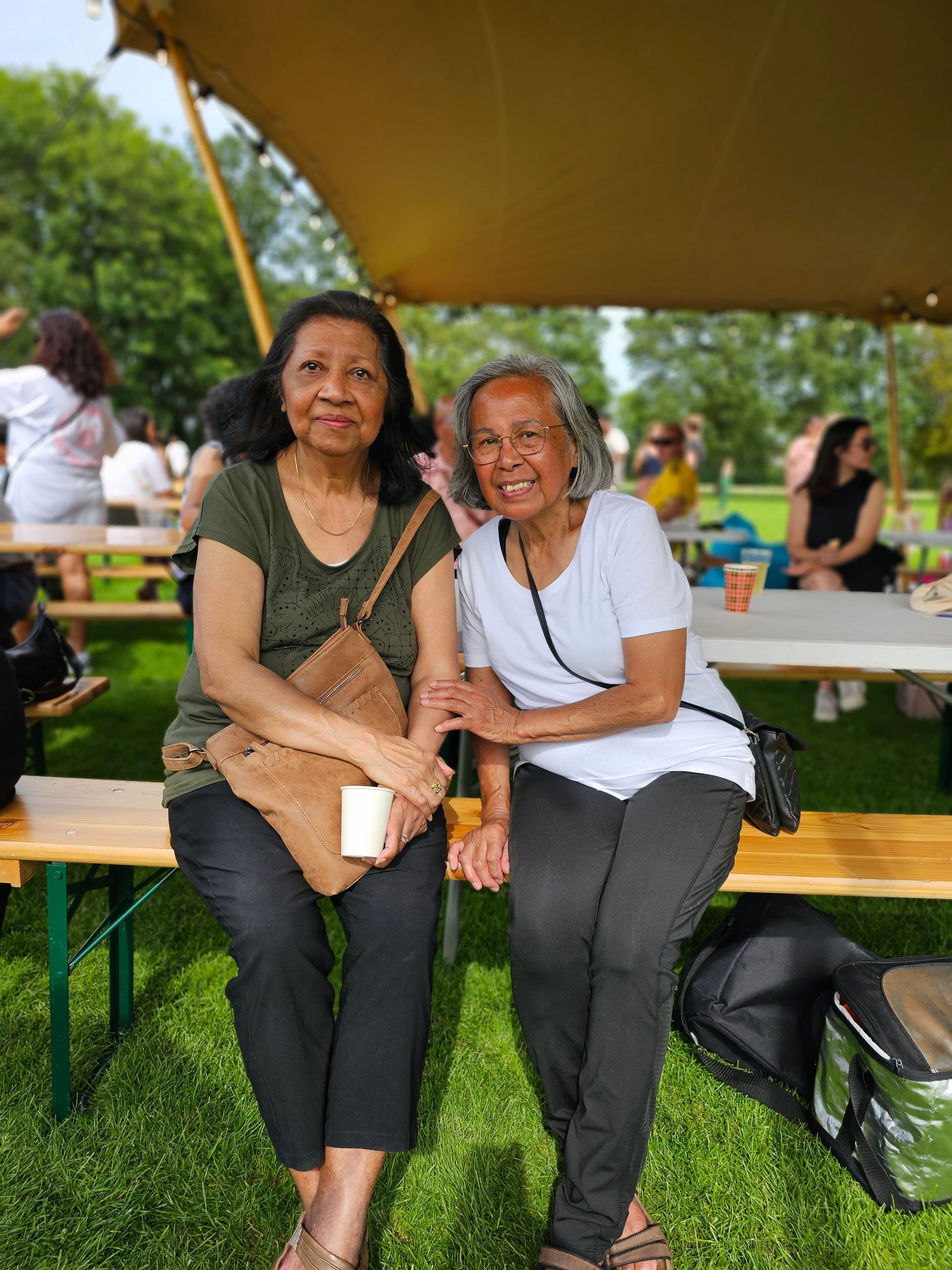 Twee vrouwen zitten op een bankje in een park.