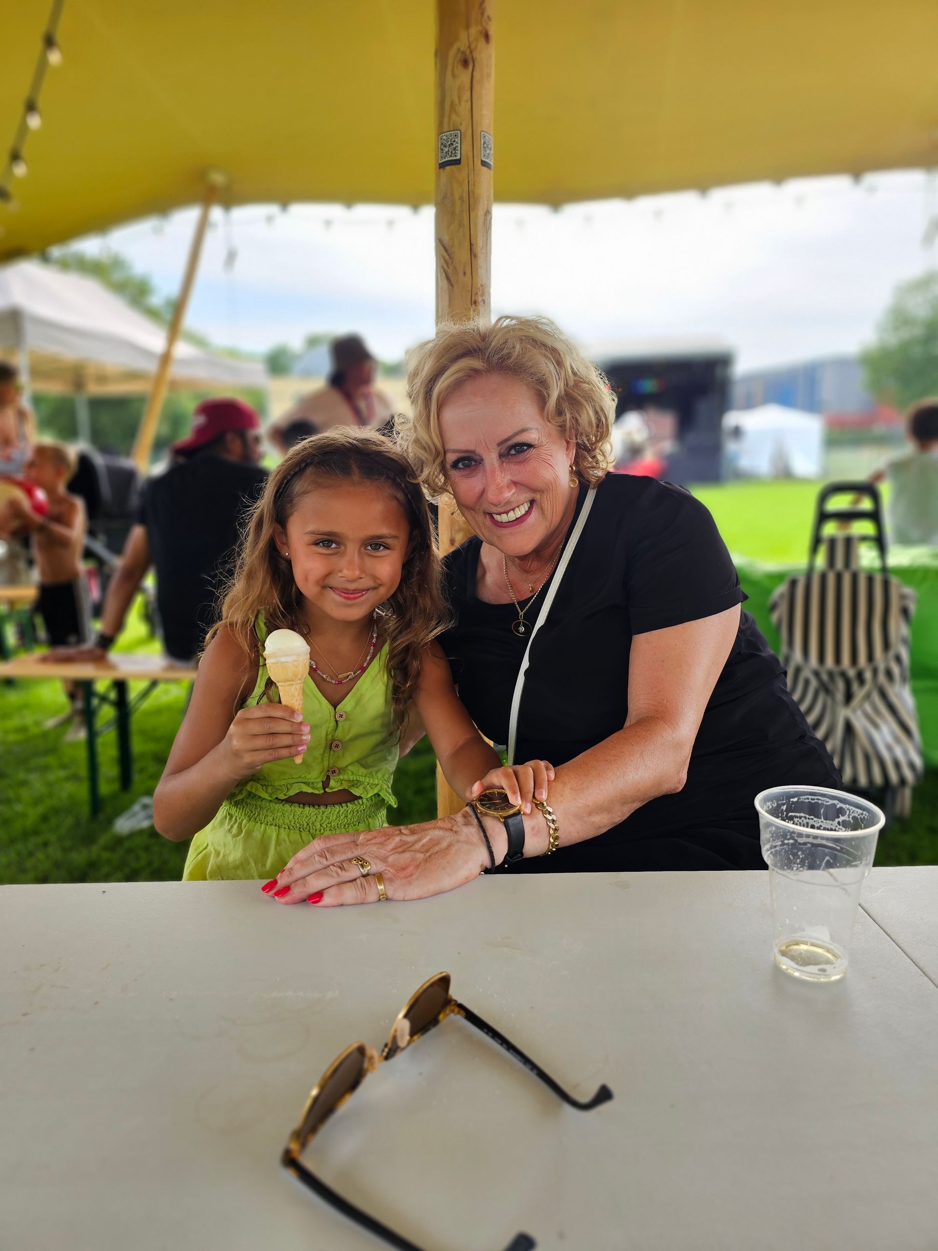 Een vrouw en een klein meisje zitten aan een tafel ijs te eten.