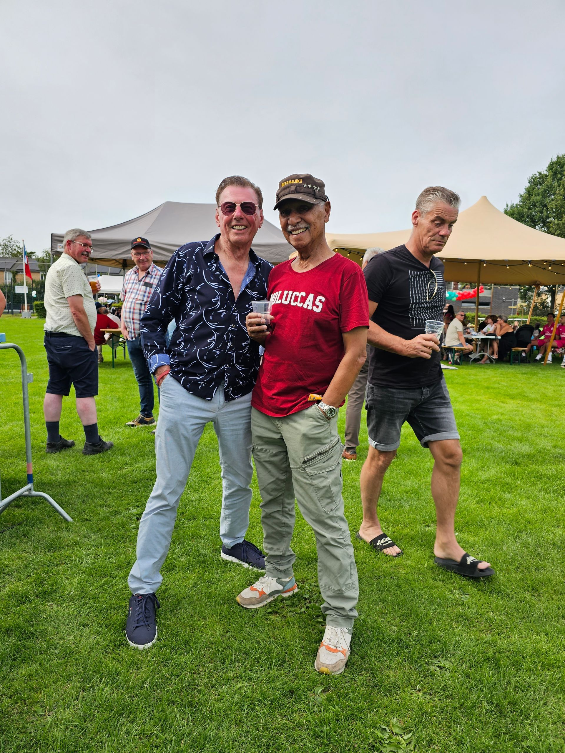 Drie mannen poseren voor een foto in een grasveld.