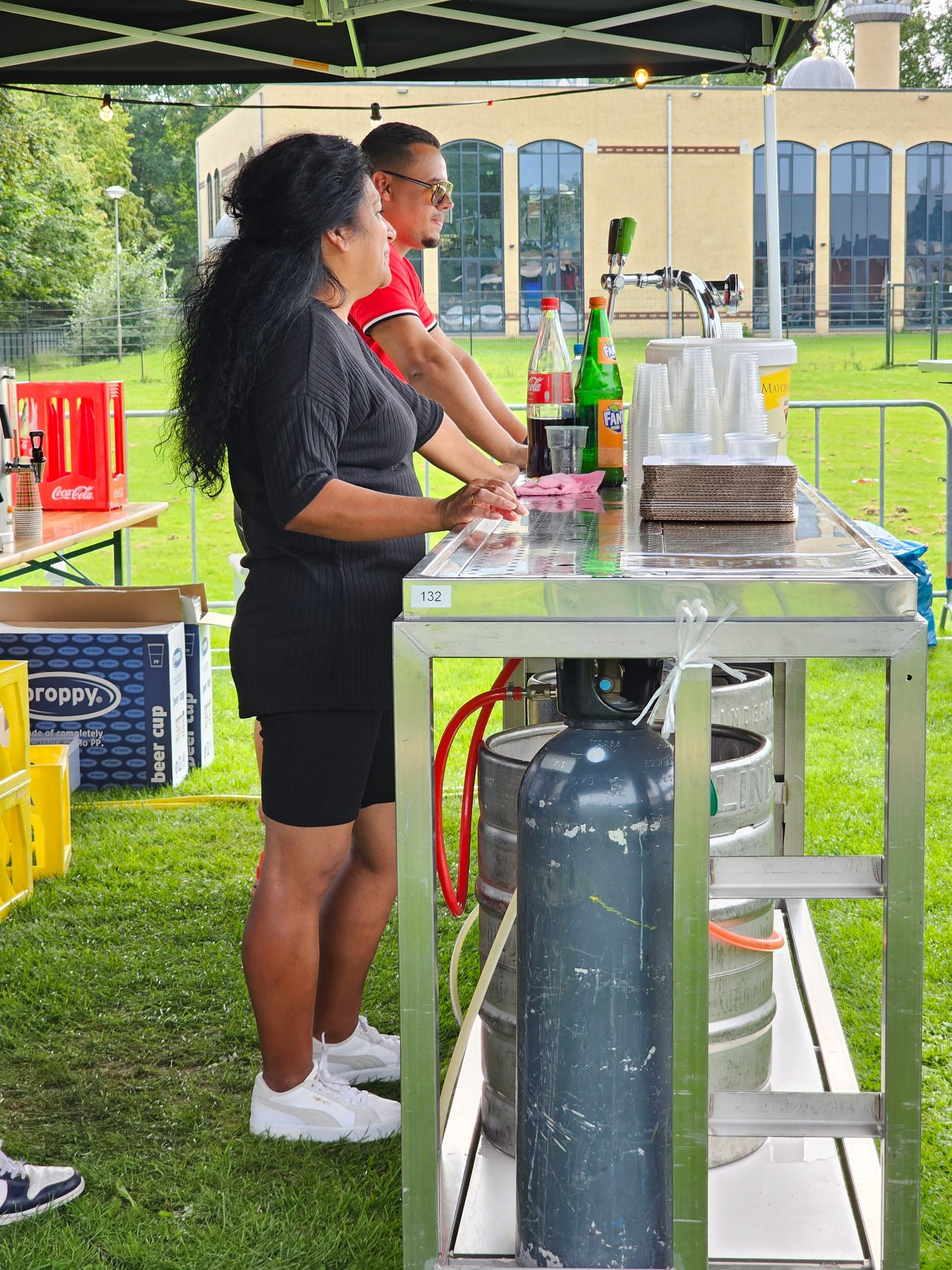 Een vrouw staat voor een tafel met flessen erop.