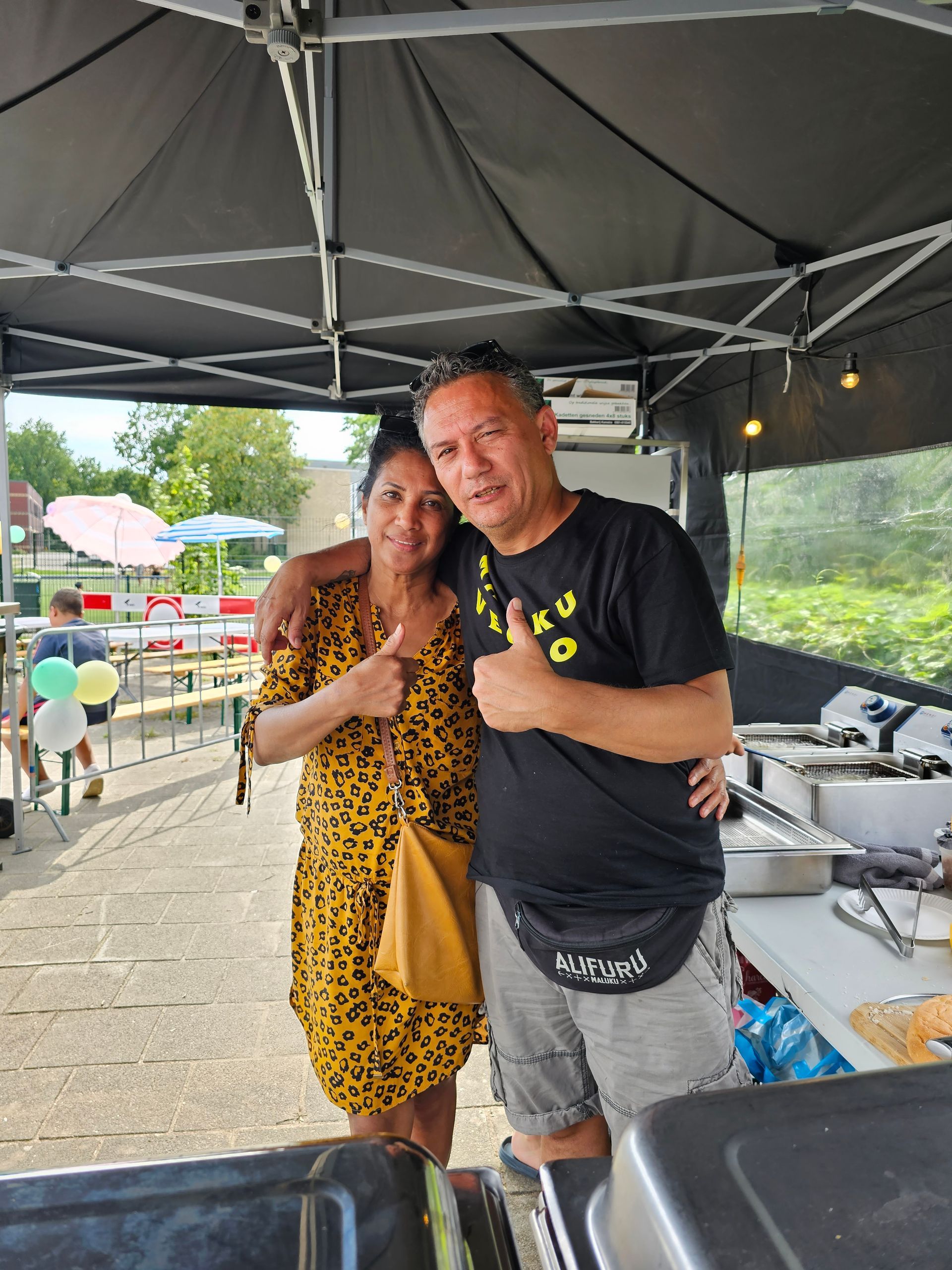 Een man en een vrouw poseren voor een foto onder een tent.