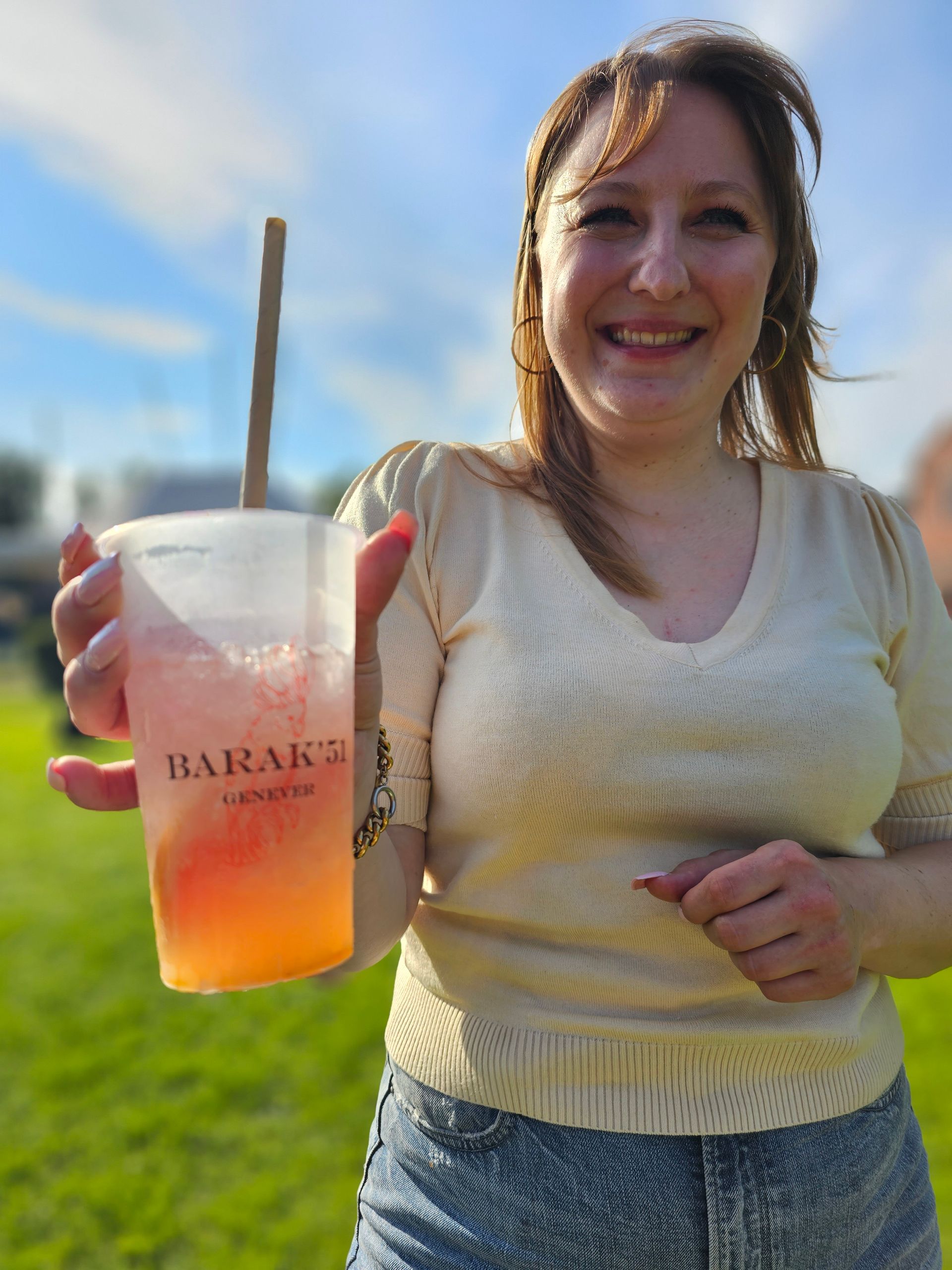 Een vrouw houdt een plastic beker met een rietje in haar hand.