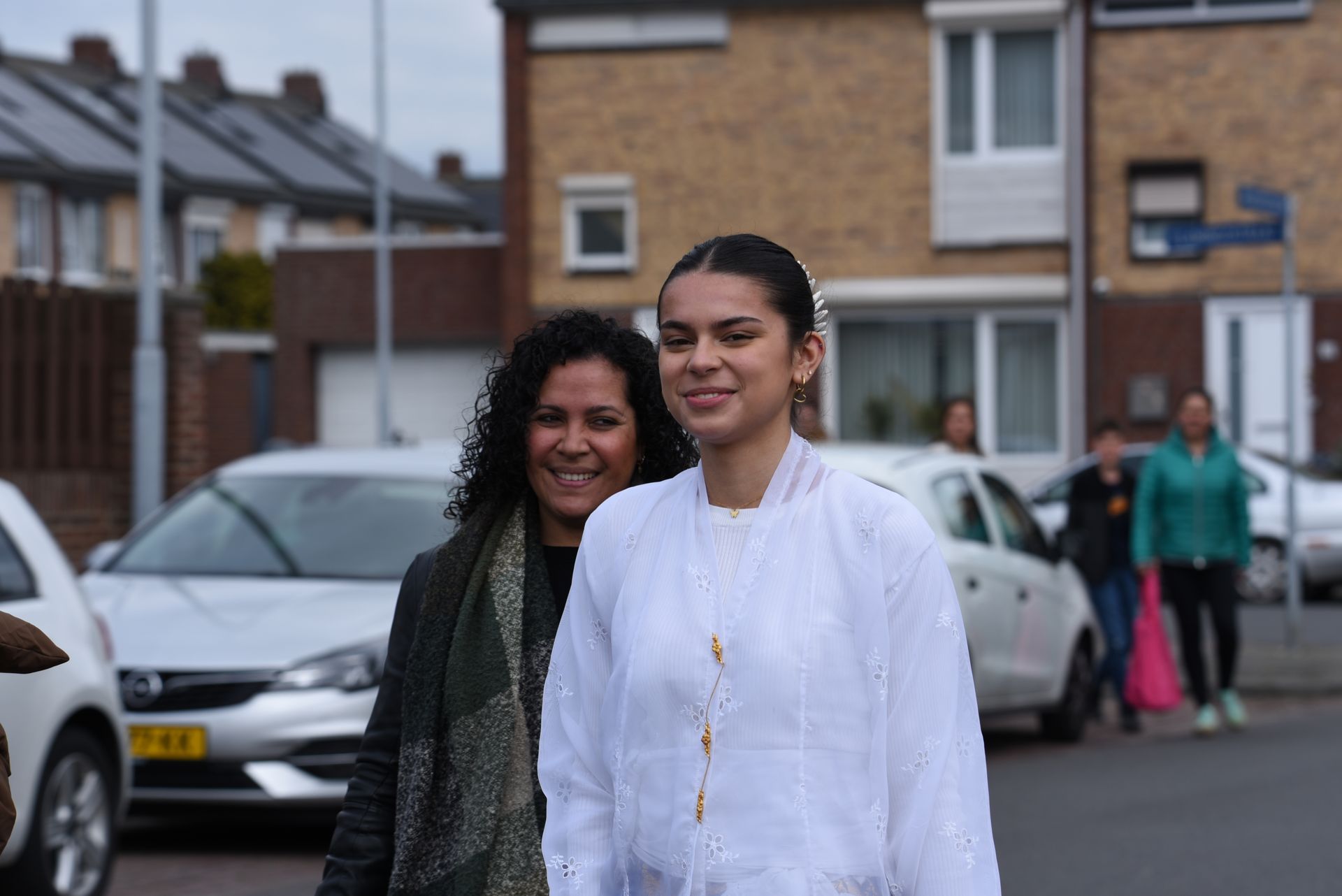 Twee vrouwen lopen door de straat voor een rij huizen.
