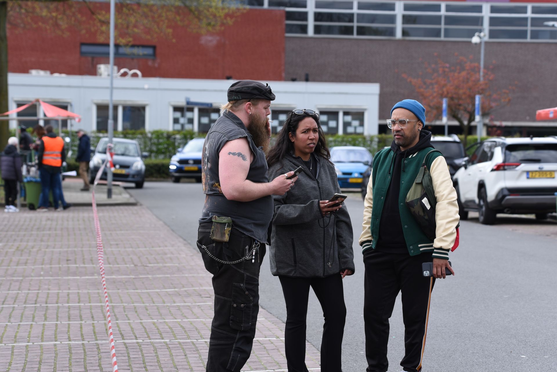 Een groep mensen staat op een parkeerplaats naar hun telefoons te kijken.